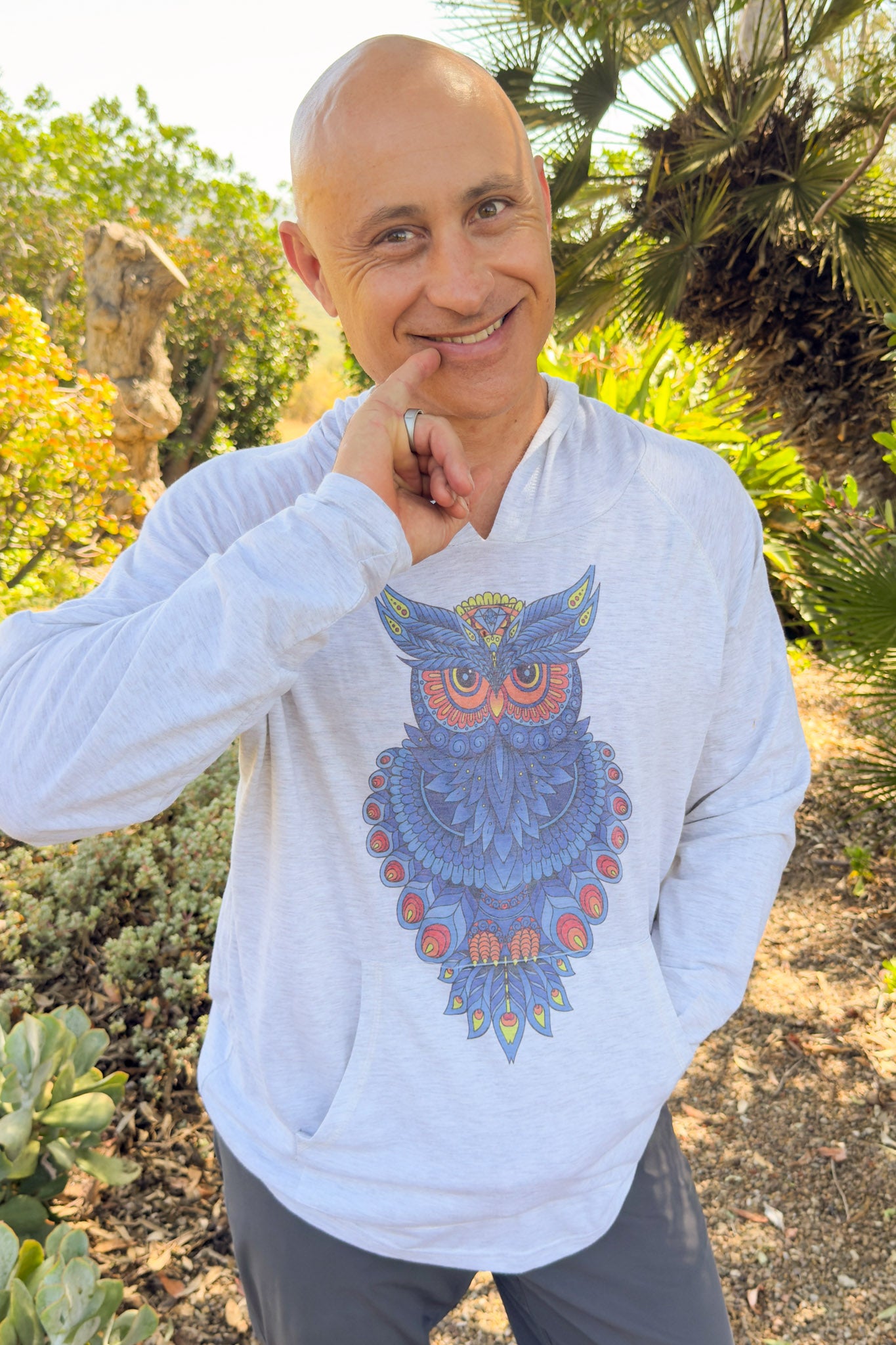 Man wearing a hoodie with an owl design outdoors